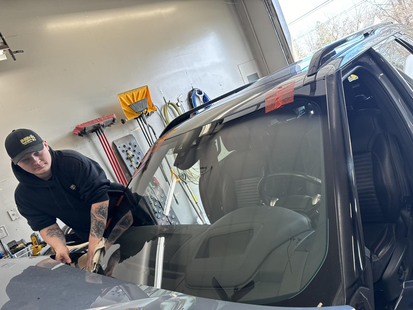B-Rite tech finishing a windshield installation wearing branded hat and gloves